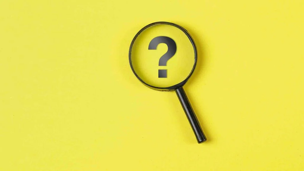 business-financial-concept-with-magnifying-glass-question-mark-yellow-background-flat-lay