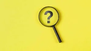 business-financial-concept-with-magnifying-glass-question-mark-yellow-background-flat-lay
