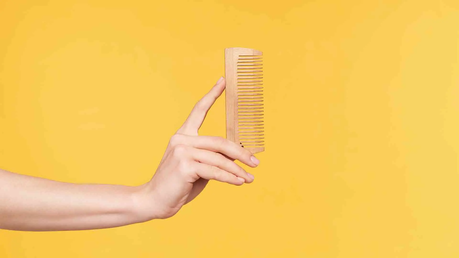 side-view-young-well-groomed-woman-s-hands-keeping-upright-wooden-while-going-comb-hair-isolated-orange-background-haircare-human-hands-concept