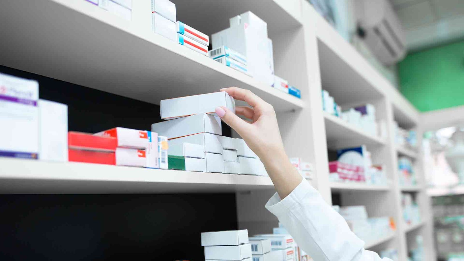 closeup-view-pharmacist-hand-taking-medicine-box-from-shelf-drug-store